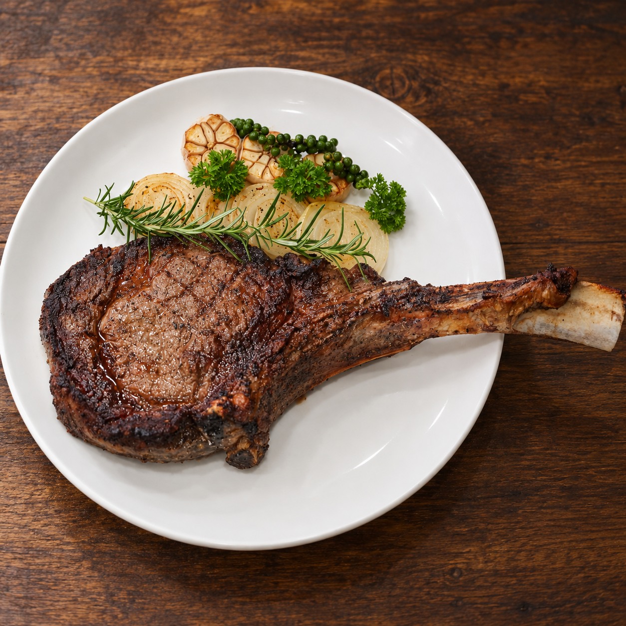 Tomahawk Wagyu MB5+ phục vụ trên đĩa với tỏi nướng, hành nướng và tiêu xanh